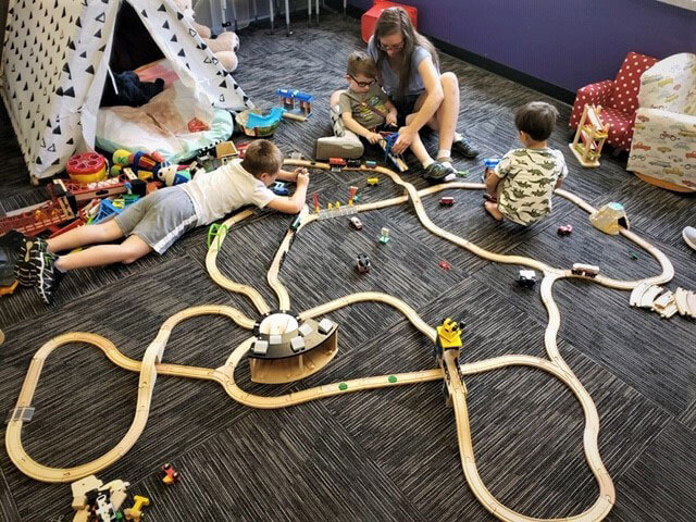 therapist and three children playing with a wooden train set
